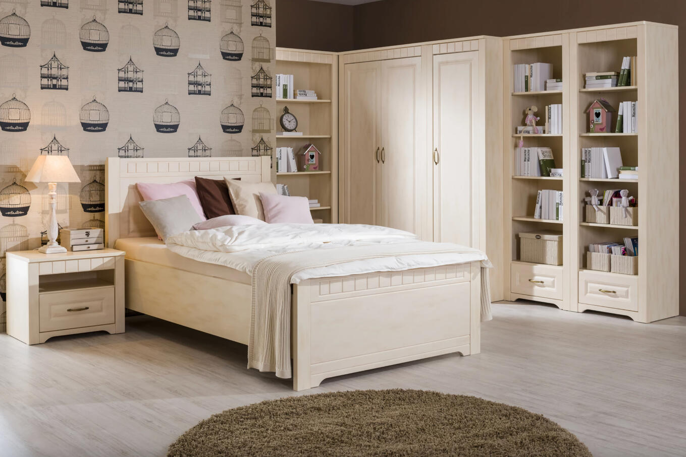 Útulná spálňa Decodom Tirol vo farbe vanilka patina, s prírodným dreveným nábytkom, pohodlnou posteľou a knižnicou.