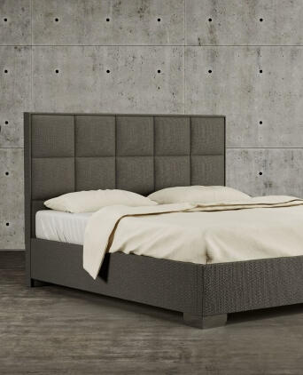 Čalúnená posteľ na mieru s vysokým štvorcovým čelom – Materasso Tmavosivá čalúnená posteľ Vega s vysokým prešívaným čelom od značky Materasso, na betónovej podlahe